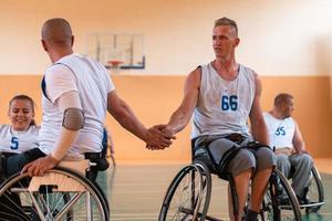 ein Team von Kriegsveteranen in Rollstühlen, die Basketball spielen und die in einem Spiel gewonnenen Punkte feiern. High-Five-Konzept foto