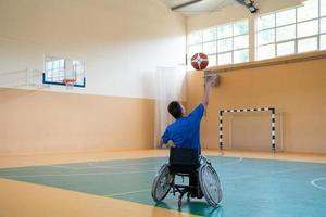 ein kriegsbeschädigter im rollstuhl trainiert mit einem ball in einem basketballverein beim training mit professionellen sportgeräten für behinderte. das Konzept des Sports für Menschen mit Behinderungen foto