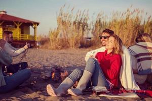 Paar genießt mit Freunden den Sonnenuntergang am Strand foto