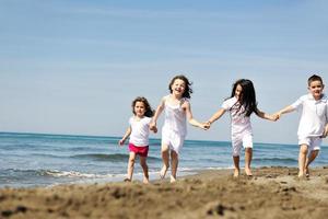 glückliche Kindergruppe, die am Strand spielt foto