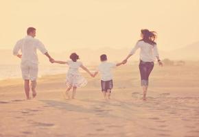 glückliche junge familie hat spaß am strand bei sonnenuntergang foto