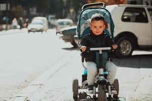 süßer kleiner Junge in einem Kinderwagenfahrrad im Freien. kleines Kind im Kinderwagen. Kleinkind in einem Kinderwagen. Frühlingswanderungen mit Kindern. foto