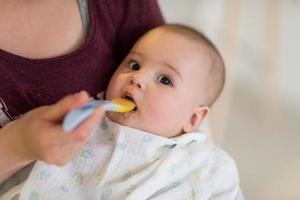 Mutter mit Löffel füttert kleines Baby foto