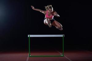 Sportlerin springt über Hürden foto