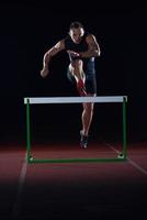 Sportler springt über eine Hürde foto