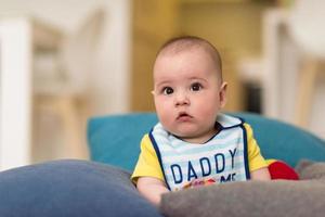 kleiner Junge sitzt zwischen den Kissen auf dem Sofa foto