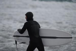 arktischer surfer, der nach dem surfen am strand vorbeigeht foto