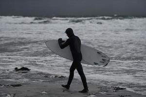 arktischer surfer, der nach dem surfen am strand vorbeigeht foto