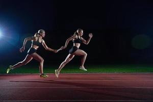 athletische läufer, die den stab im staffellauf übergeben foto