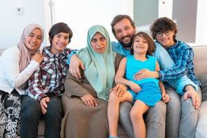 Porträtfoto einer arabischen muslimischen Familie, die auf einer Couch im Wohnzimmer eines großen modernen Hauses sitzt. selektiver Fokus foto