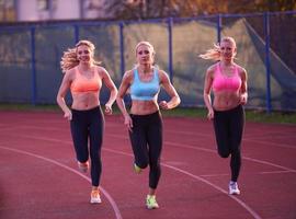 athletinnengruppe, die auf leichtathletik-rennstrecke läuft foto