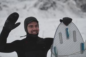 arktisches surferporträt, das ein brett nach dem surfen im norwegischen meer hält foto