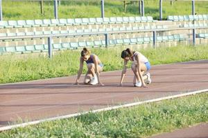 zwei mädchen, die auf einer athletischen rennstrecke laufen foto