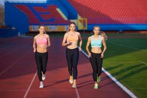 athletinnengruppe, die auf leichtathletik-rennstrecke läuft foto