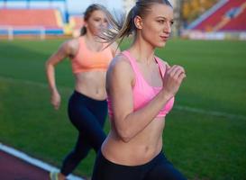 athletinnengruppe, die auf leichtathletik-rennstrecke läuft foto