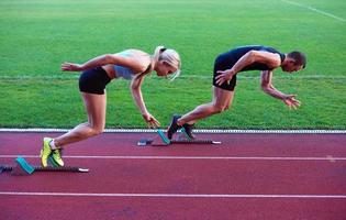 Frauengruppe, die von Anfang an auf der Leichtathletik-Rennstrecke läuft foto