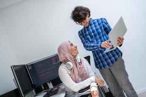 Startup-Unternehmen, junge Kreativprofis, die sich über ein Treffen in einem hellen Büro unterhalten, während sie auf einen Computer mit zwei Bildschirmen zeigen, um Vorschläge und Hilfe bei Projekten zu erhalten foto