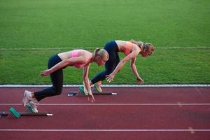 athletinnengruppe, die auf leichtathletik-rennstrecke läuft foto