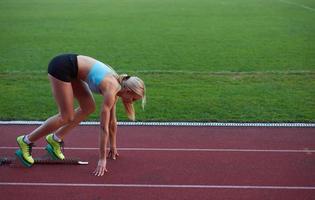 athletinnengruppe, die auf leichtathletik-rennstrecke läuft foto