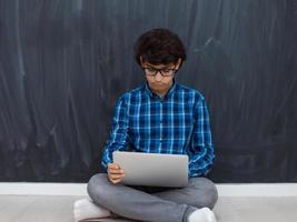 arabischer teenager, der einen laptop verwendet, um an hausaufgaben zu arbeiten und online-bildung anzusehen, während er zu hause bleibt, verursacht eine coronavirus-pandemie-quarantäne foto