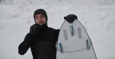 arktisches surferporträt, das ein brett nach dem surfen im norwegischen meer hält foto