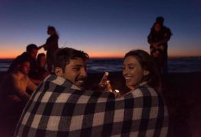 Paar genießt mit Freunden den Sonnenuntergang am Strand foto