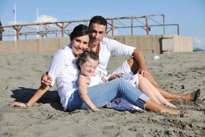 glückliche familie, die mit hund am strand spielt foto