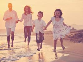 glückliche junge familie hat spaß am strand bei sonnenuntergang foto