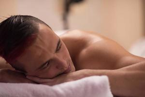 Schöner Mann, der sich in einem Spa-Massagezentrum ausruht foto