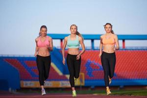 athletinnengruppe, die auf leichtathletik-rennstrecke läuft foto