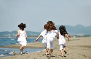 glückliche Kindergruppe, die am Strand spielt foto