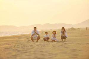 glückliche junge familie hat spaß am strand bei sonnenuntergang foto