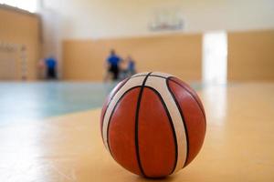 Nahaufnahmefoto eines Basketballs auf dem Platz, im Hintergrund eine Sportmannschaft von Menschen mit Behinderungen, die sich auf ein Spiel vorbereiten foto