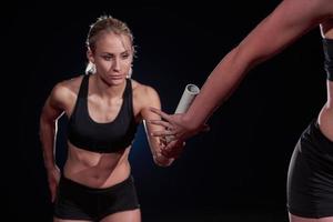 athletische läufer, die den stab im staffellauf übergeben foto