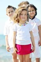 glückliche Kindergruppe, die am Strand spielt foto