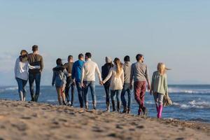 gruppe von freunden, die während des herbsttages am strand laufen foto