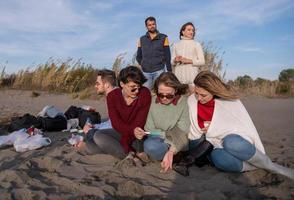 freunde, die sich am herbsttag am strand vergnügen foto