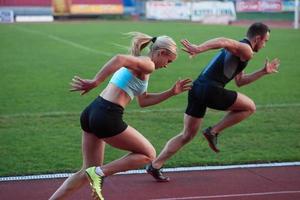 athletinnengruppe, die auf leichtathletik-rennstrecke läuft foto