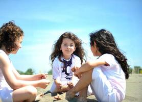 glückliche Kindergruppe, die am Strand spielt foto