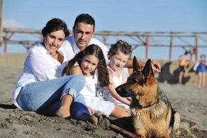 glückliche familie, die mit hund am strand spielt foto