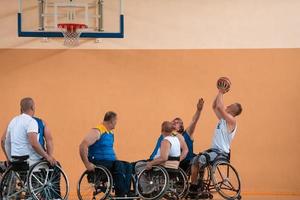 Behinderte Kriegsveteranen gemischte Rassen- und Alters-Basketballteams in Rollstühlen, die ein Trainingsspiel in einer Sporthalle spielen. Rehabilitations- und Inklusionskonzept für behinderte Menschen foto