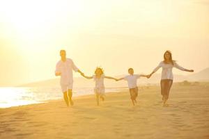 glückliche junge familie hat spaß am strand bei sonnenuntergang foto