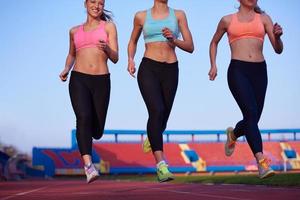 athletinnengruppe, die auf leichtathletik-rennstrecke läuft foto