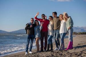 Porträt von Freunden, die sich während des Herbsttages am Strand amüsieren foto