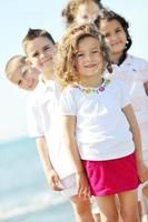 glückliche Kindergruppe, die am Strand spielt foto