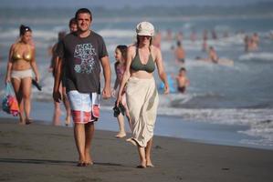 glückliches Paar, das am Strand spazieren geht foto