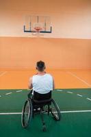 ein Foto eines Kriegsveteranen, der in einer modernen Sportarena Basketball spielt. das Konzept des Sports für Menschen mit Behinderungen