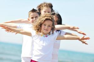 glückliche Kindergruppe, die am Strand spielt foto