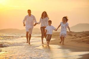 glückliche junge familie hat spaß am strand bei sonnenuntergang foto