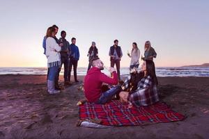 Paar genießt mit Freunden den Sonnenuntergang am Strand foto